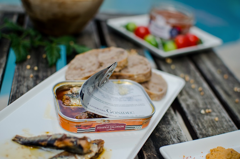Opened can of small sardines in extra virgin olive oil with Espelette hot chili pepper