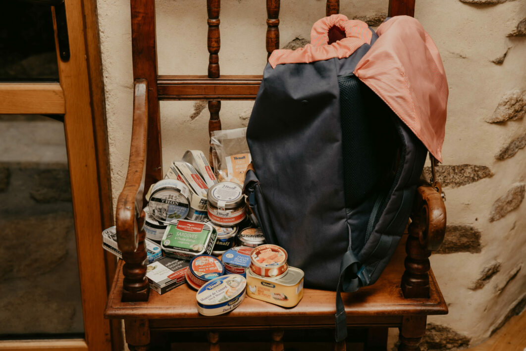 A backpack for a hike full of canned seafood and meat food